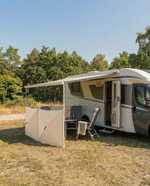 Husbil med utfälld markis och campingstolar utomhus i naturen – Smart Camping tillbehör för husbil och husvagn